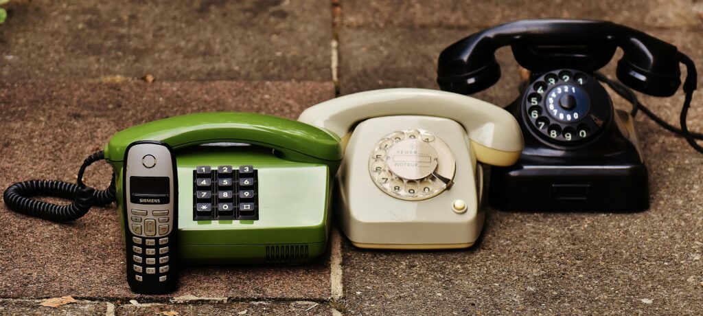pexels photo 207456 207456 A variety of antique, vintage, and modern telephones displayed on pavement.