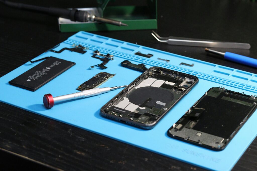 pexels photo 31862950 31862950 Close-up of disassembled smartphone parts on a blue repair mat with tools.